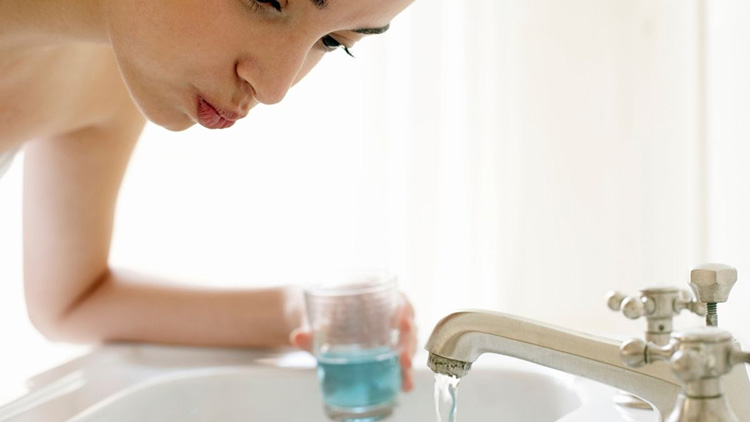 woman rinsing mouth with water